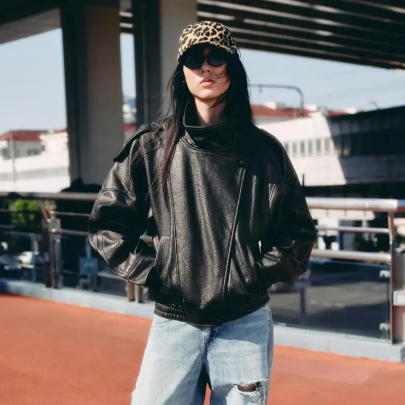 Veste bomber en cuir de litchi noir pour femmes, présentant un matériau en cuir noir avec un col montant et des poches zippées.
