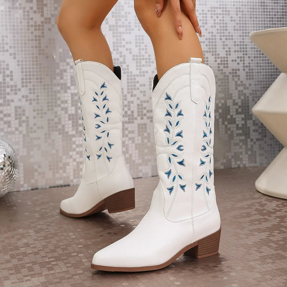 White leather embroidered western cowboy boots with blue leaf patterns and brown chunky block heels.