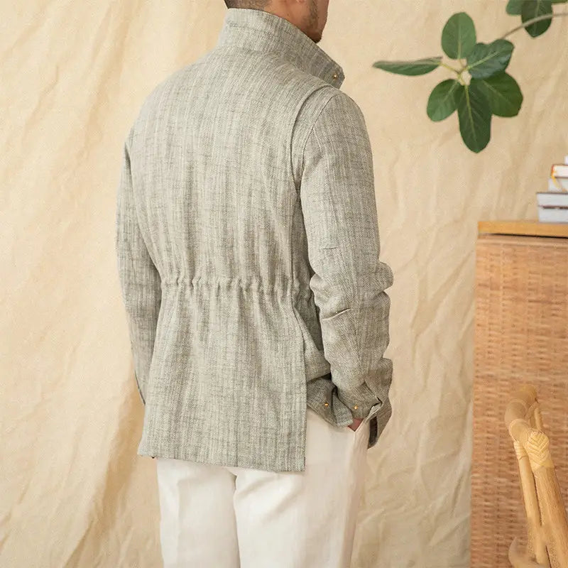 A light gray cotton linen M65 safari jacket with textured fabric, a high collar, and an elasticated waistband.