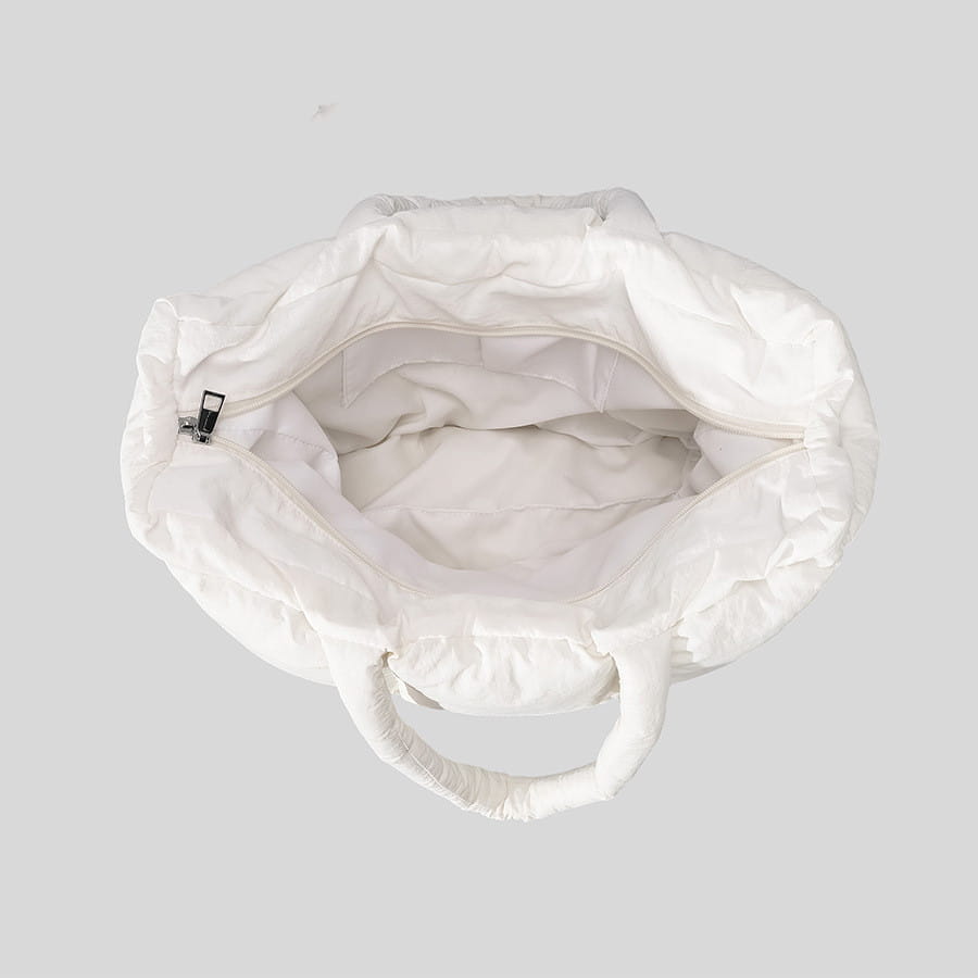 Bolsa tote acolchada tipo puffer blanca con tejido de algodón suave y asas a juego, diseñada como un bolso elegante.