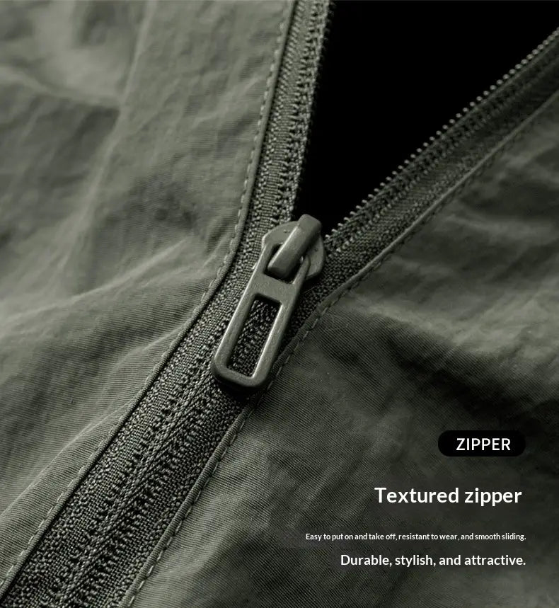 Fermeture éclair grise métallisée texturée avec une languette robuste sur une veste légère coupe-vent imperméable zippée pour homme en vert foncé.