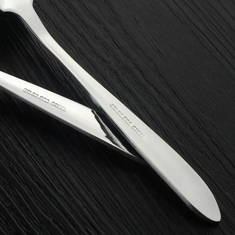 Cuillère à pamplemousse en acier inoxydable brillant, avec un design moderne et épuré, et une tête de racloir à fruits à dents, comportant un motif en acier inoxydable gravé sur le manche.