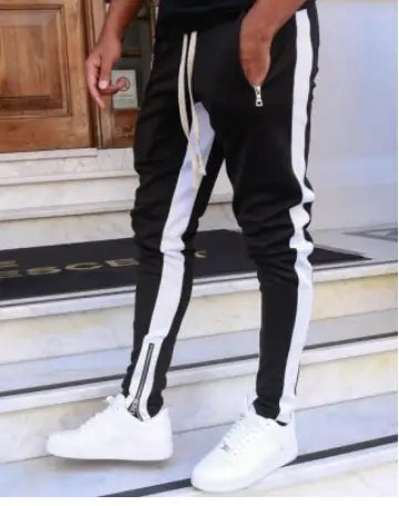 Men’s black athletic joggers with white side stripes and zipper cuffs designed for fitness and casual wear.