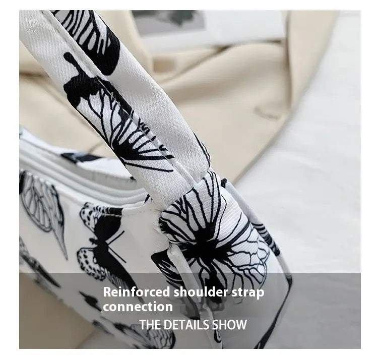 Sangle de sac bandoulière blanche avec motifs de papillon et floraux noirs, renforcée au point de jonction sur un sac sous-bras en nylon à imprimé léopard et à carreaux