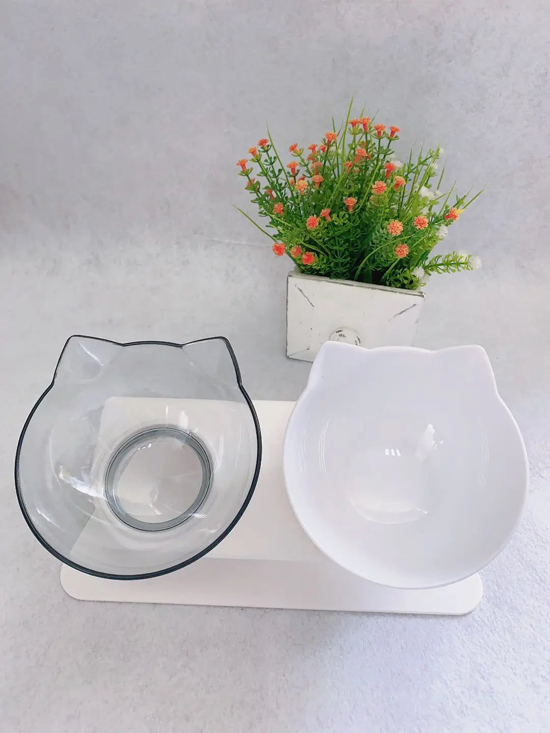 Elevated cat bowl tilted 15 degree double feeder stand with clear and white cat-shaped pet bowls featuring black trim on the clear bowl designed for feeding or watering pets.