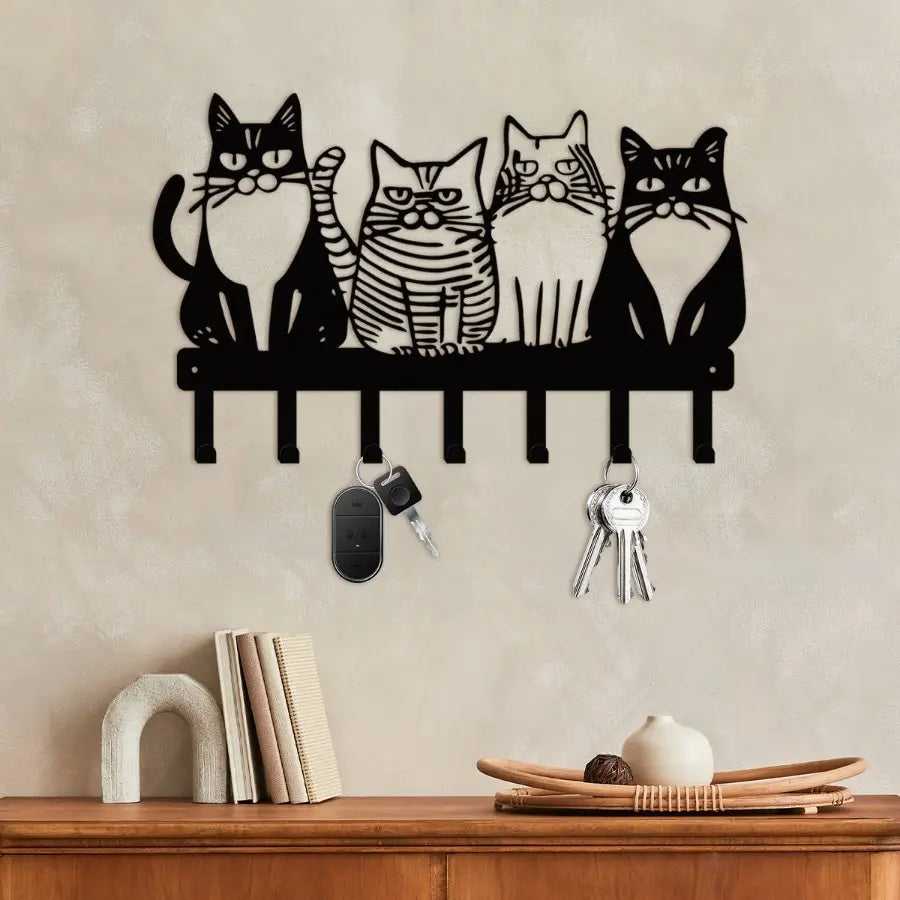 Black metal wall-mounted key holder featuring four stylized cat silhouettes with distinct expressions and striped patterns on a shelf base with four hooks for keys in black metal home decor.