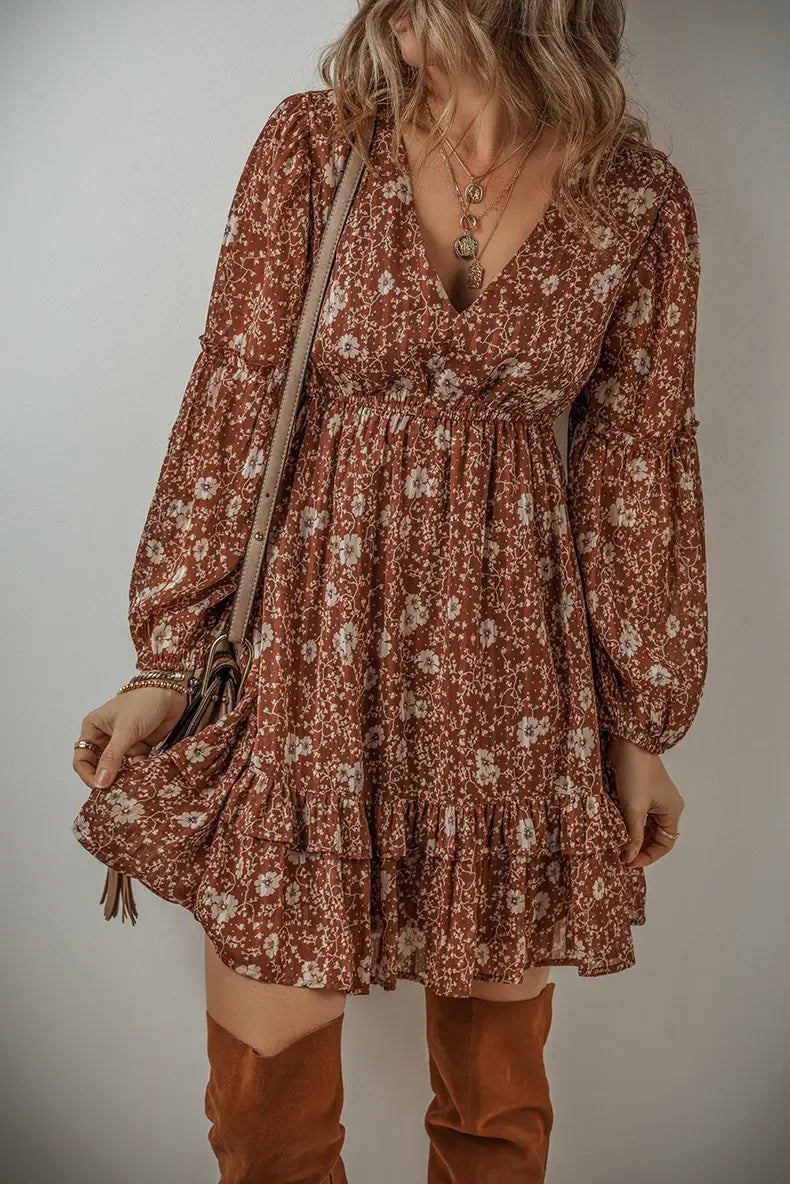 A rust-colored floral print bohemian mini dress with long puff sleeves and a ruffled tiered hem.
