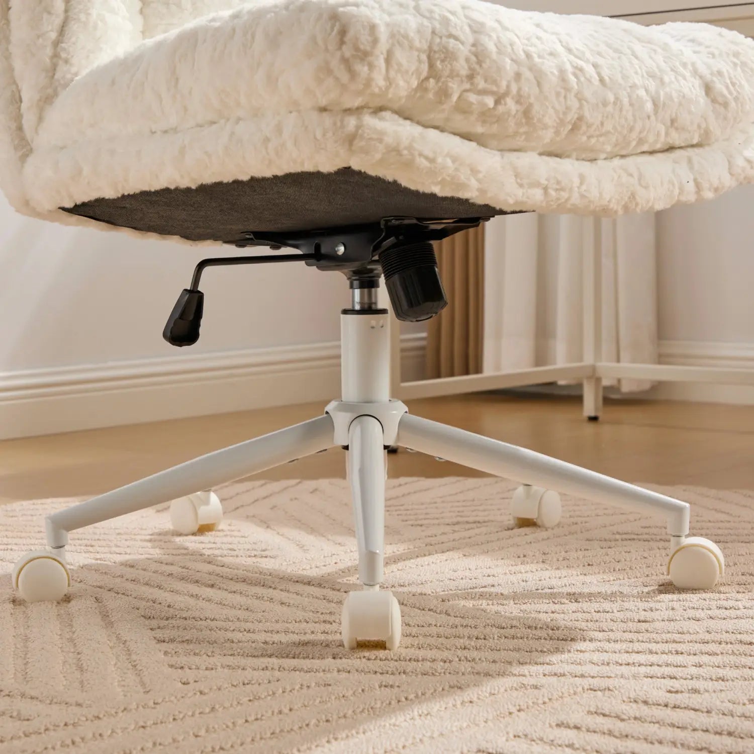 Chaise de bureau en fausse fourrure duveteuse couleur crème, avec design de pivotement de l’assise large, base blanche en métal et roues à roulettes pour un usage de vanité ou de bureau.