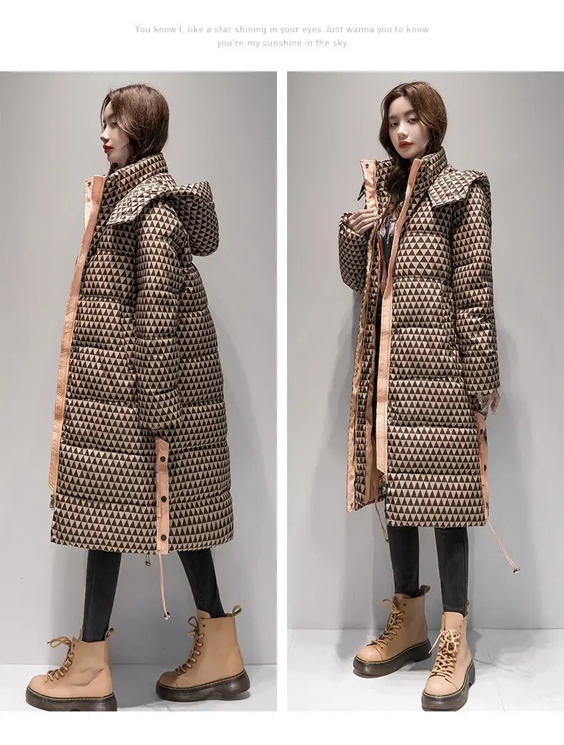 Un long manteau matelassé en coton à carreaux pour femmes avec un motif géométrique de triangles marron et beige, doté d’une capuche, d’une fermeture à glissière à l’avant et d’une finition brun rosé le long des côtés.