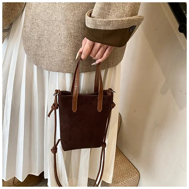 Retro leopard print suede mini bucket crossbody bag with brown suede body, tan leather handles, and a matching adjustable strap.
