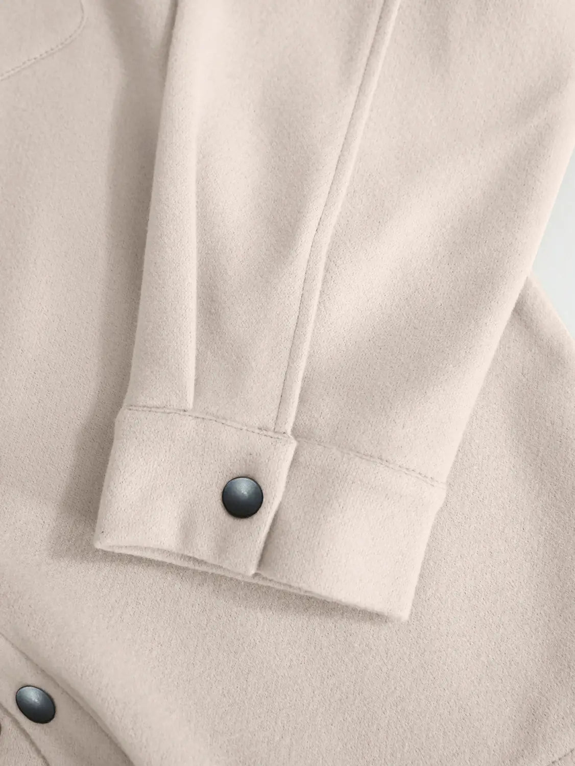 Beige woolen sleeve with a single dark button at the cuff of a men’s classic slim fit wool blend lapel jacket.