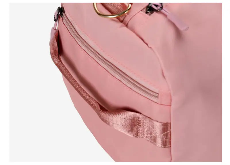 Pink nylon waterproof oxford travel duffel with gold-tone metal zipper pulls and a matching pink fabric strap designed for gym and sports use.