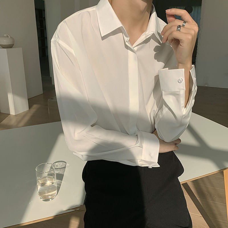 A crisp white retro drape wrinkle resistant satin button down shirt with a classic collar and neatly folded cuffs.
