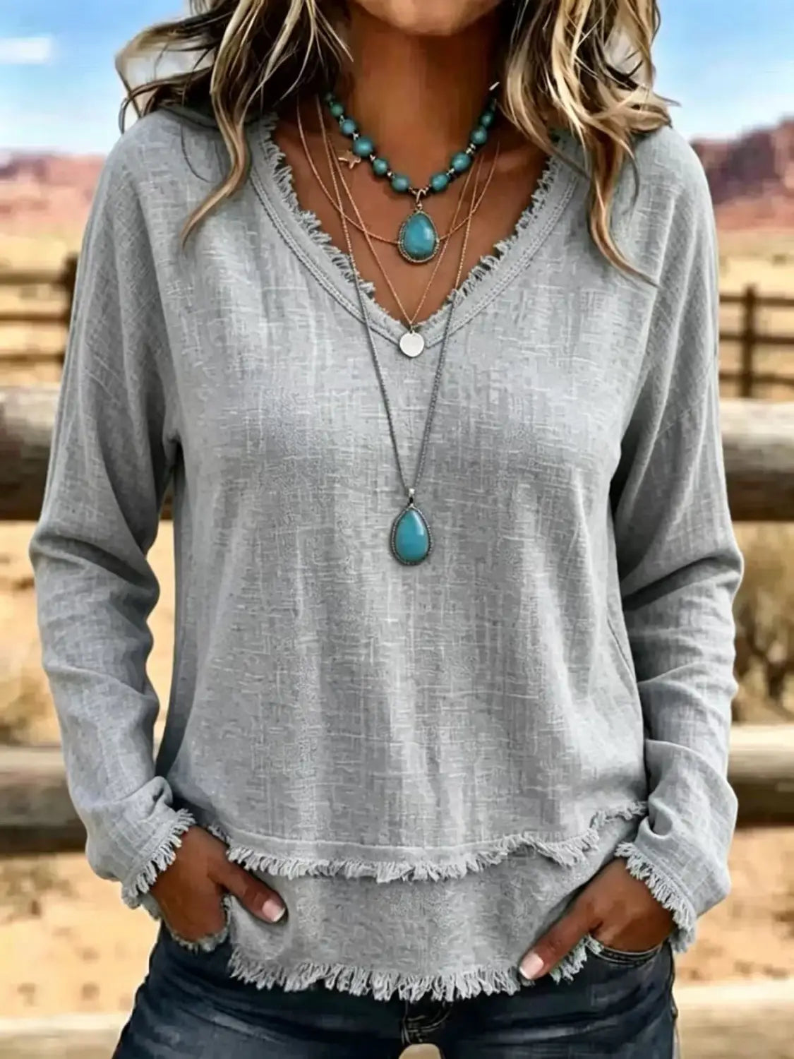 T-shirt pour femmes à manches longues et encolure en V gris, avec ourlet effiloché, adapté à un usage décontracté.