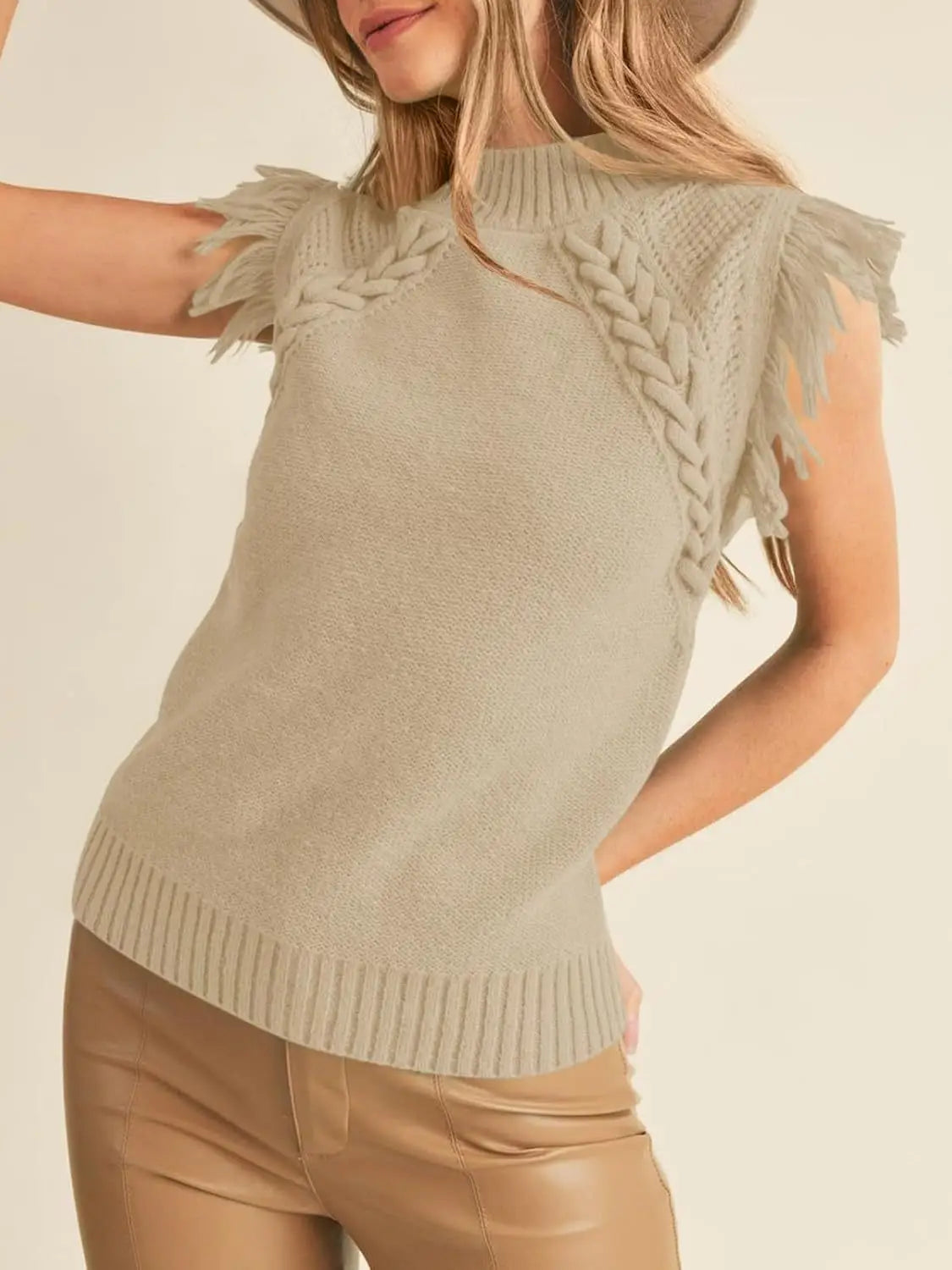 Beige hand-woven sleeveless knit sweater vest with braided shoulder details and fringe trim.