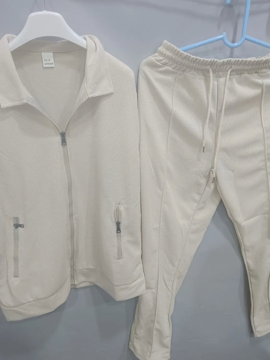 Men slim fit cream-colored textured knit two-piece tracksuit with zippered front and side pockets including jacket and pants.