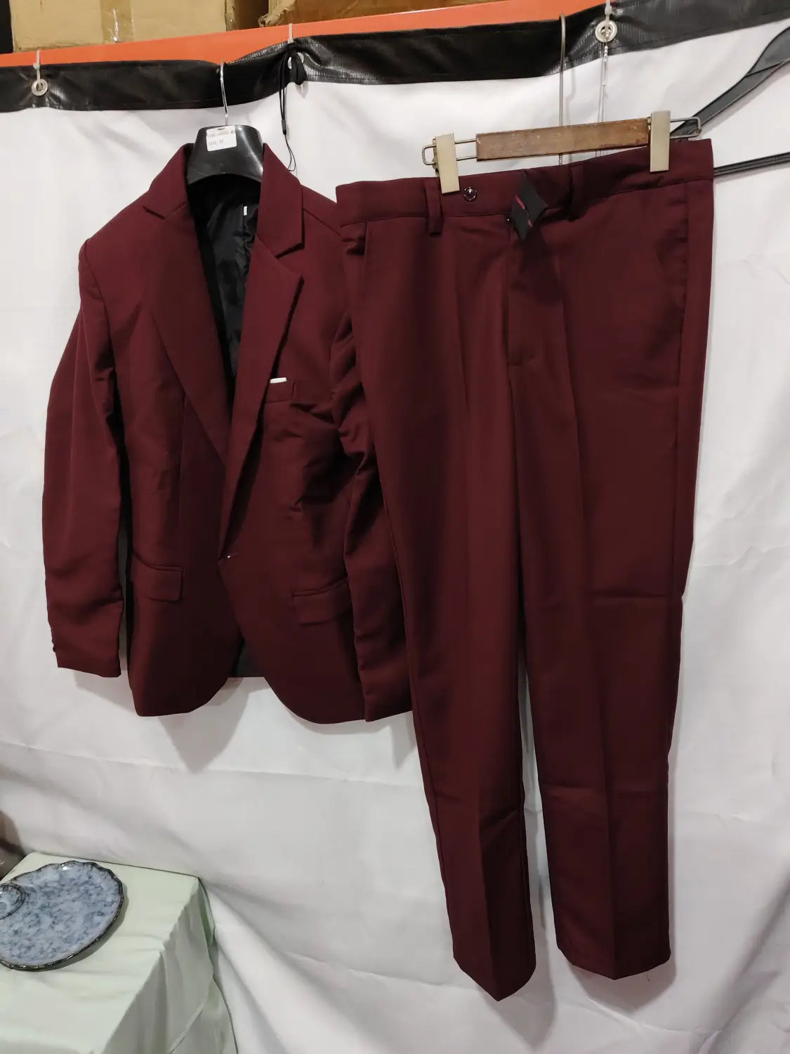 Men slim fit satin suit two piece in maroon featuring a tailored blazer and matching trousers displayed on hangers.