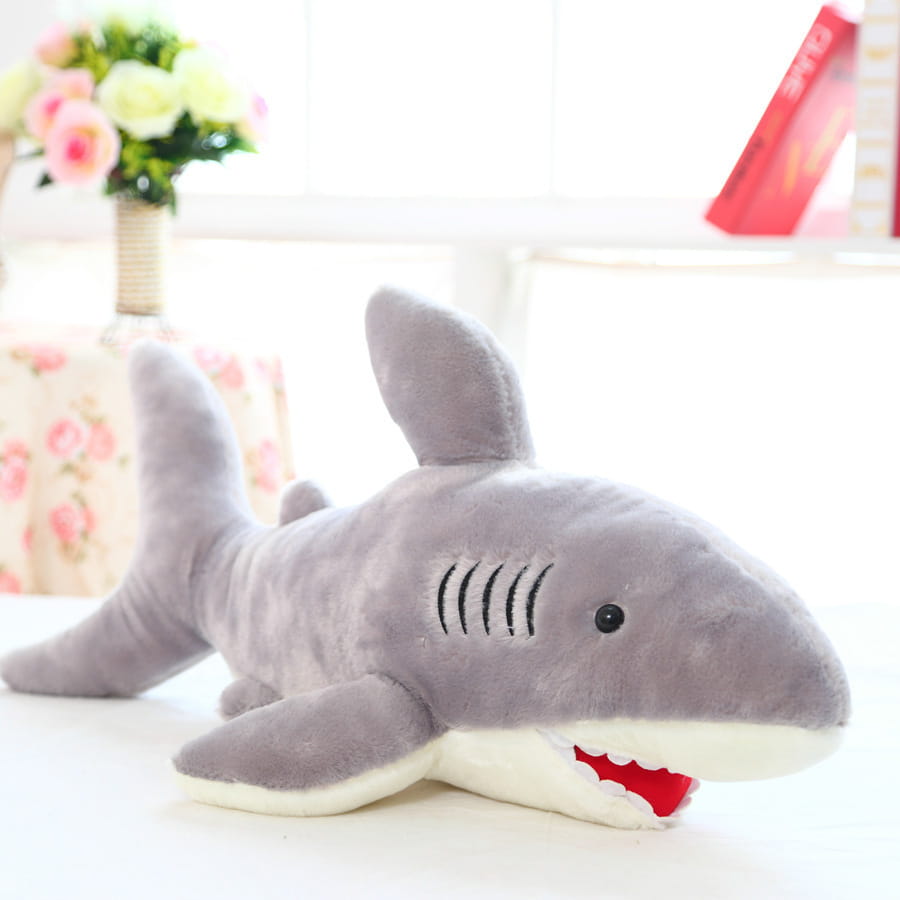 A plush gray shark toy with a white underbelly and red stitched teeth and gills.