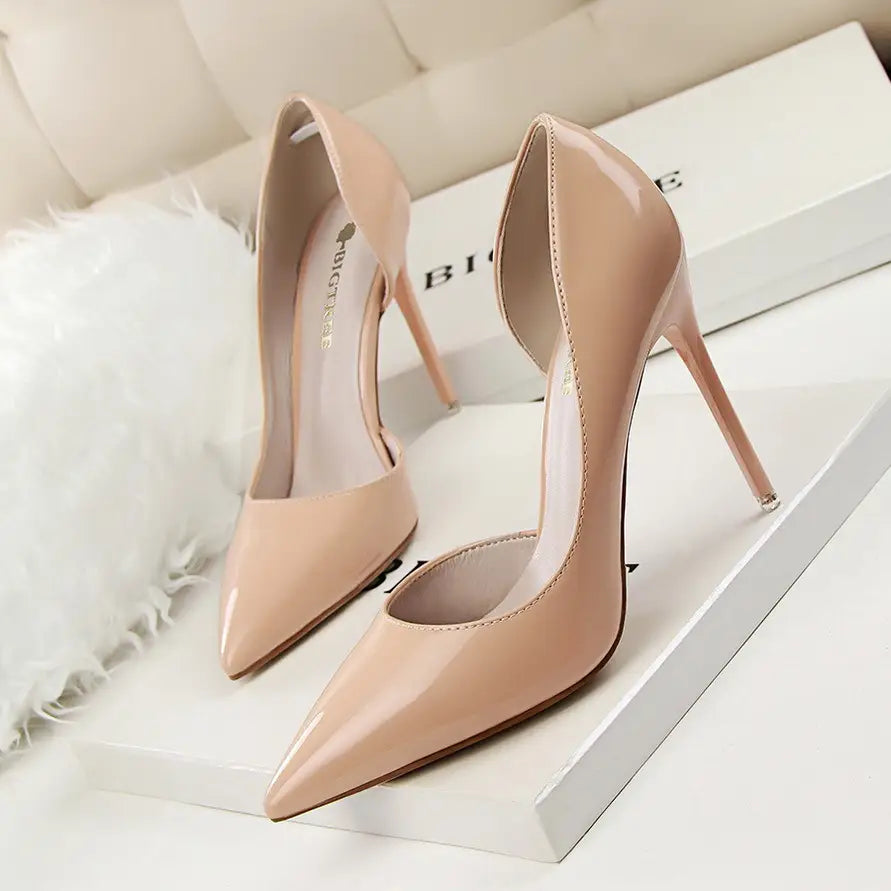 Nude patent leather high-heeled pumps with a sleek pointed toe and thin stiletto heel.