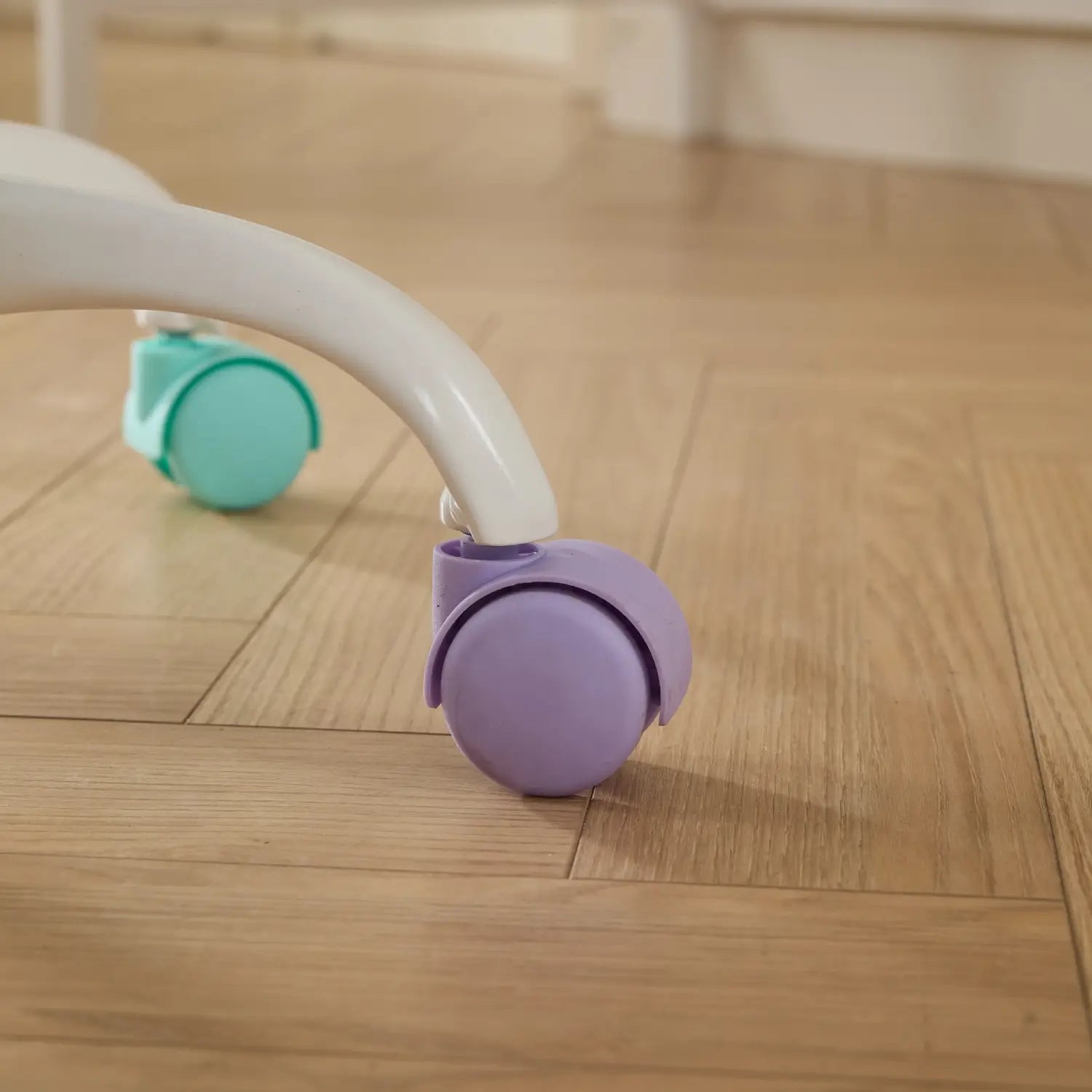roue pivotante en plastique violette fixée à un pied de fauteuil blanc d’un fauteuil de bureau en fausse fourrure violette doté de roues colorées
