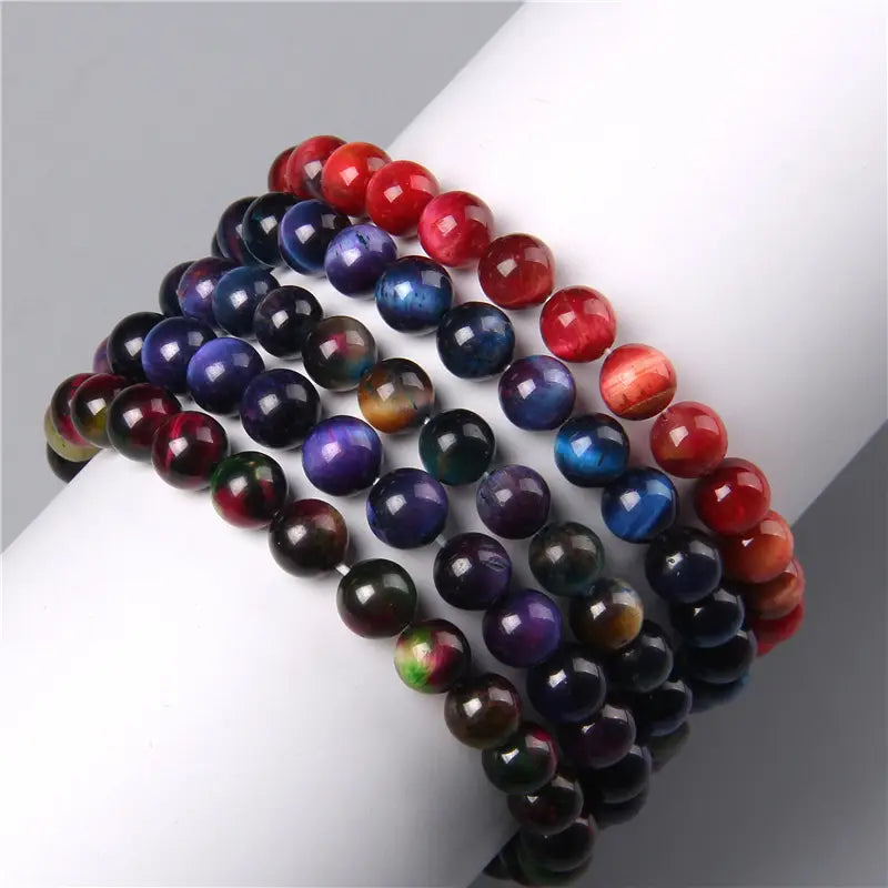 A collection of men’s 8mm natural tiger eye and gemstone bead bracelets displayed in polished red, blue, purple, and black hues.