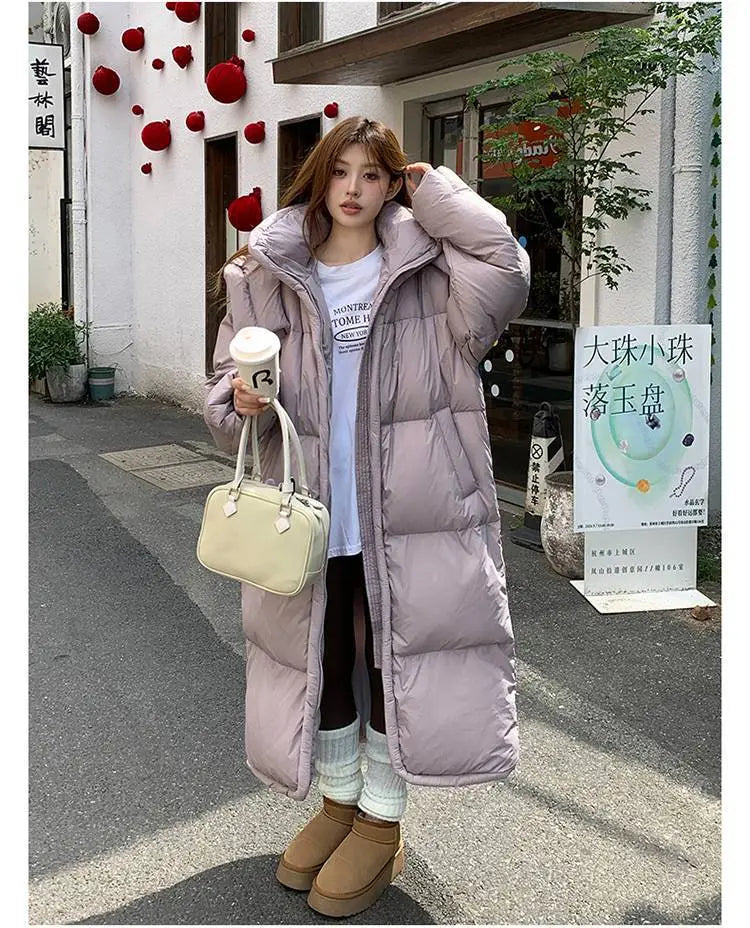 A women’s long quilted winter puffer coat in lavender featuring a high collar and front zipper made of down material.