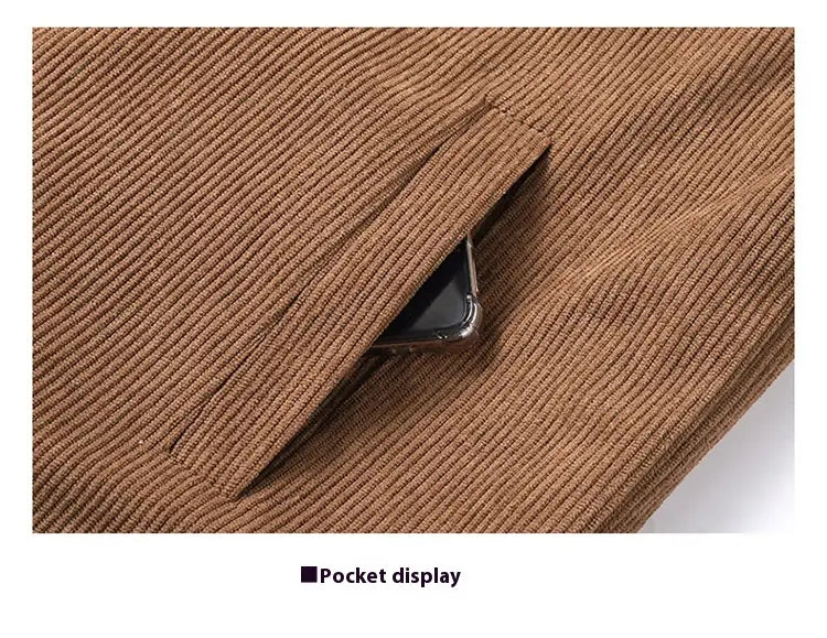 Eine braune Cordjacken-Tasche mit dezent gerippter Textur, die die Kante eines Smartphone-Displays teilweise erkennen lässt.