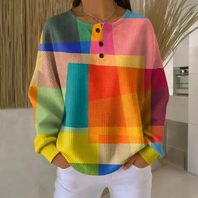 A vibrant long-sleeved henley sweatshirt for women featuring a bold rainbow geometric pattern and textured knit fabric.
