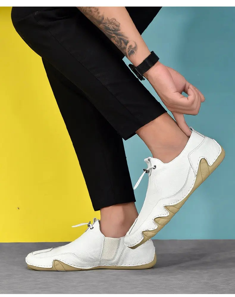 Chaussures de sport décontractées à enfiler pour homme en cuir véritable blanc, avec une semelle en caoutchouc beige et un design ondulé distinctif le long du côté.