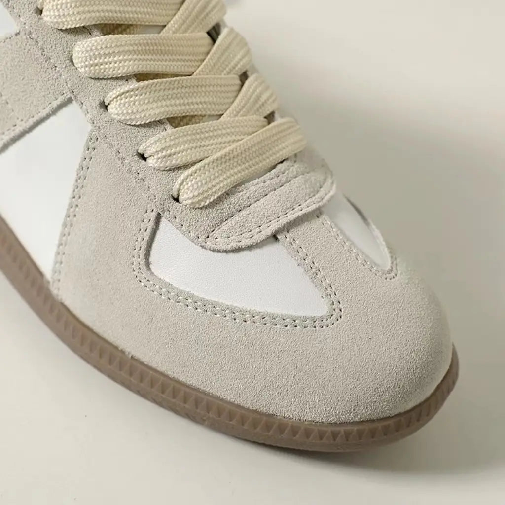 Beige Veloursleder- und weiße Ledersneaker im Low-Top-Design mit passenden beigen Schnürsenkeln, entworfen als vielseitige Freizeitschuhe.