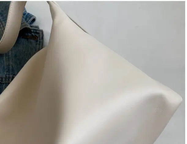 Cream-colored smooth leather shoulder bag with gold buckle and strap featuring a minimalist design.