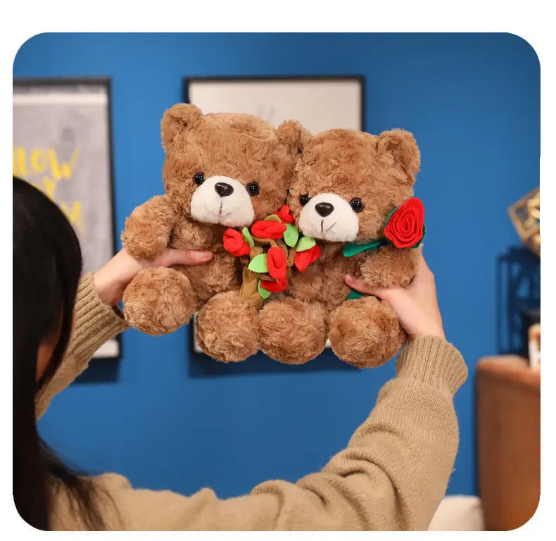Zwei braune Plüsch-Teddybären mit weißen Schnauzen und schwarzen Knopfaugen, jeder mit einer roten Filzrose auf der Brust verziert; in einem Teddybär-Plüschtier mit Rosen, Valentinsgeschenk, 16–25 cm.