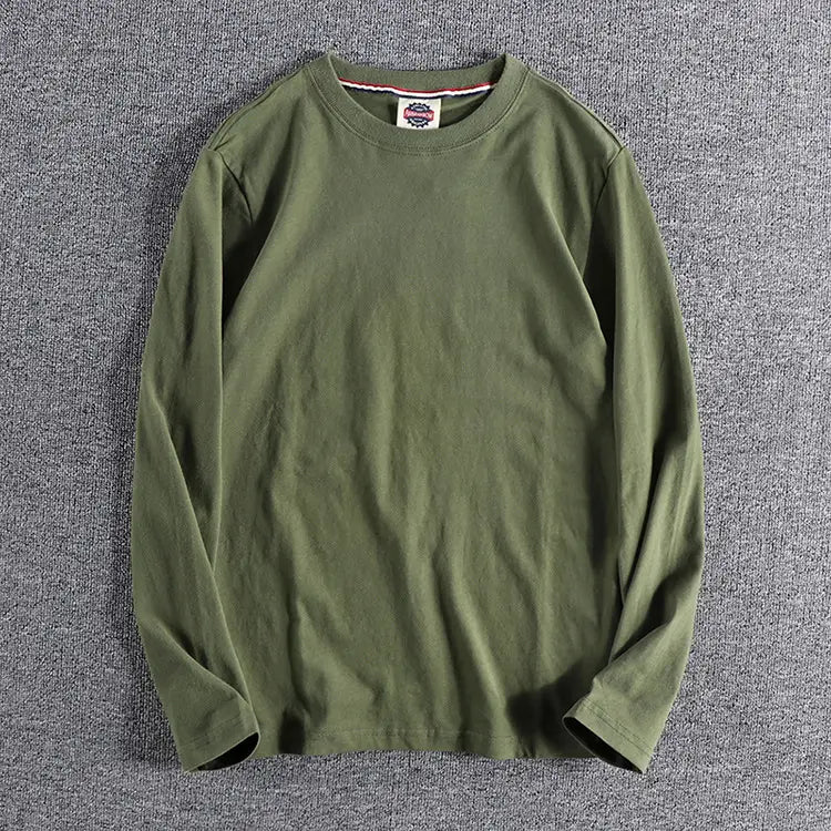 Camiseta de color liso lavado verde oliva de manga larga con cuello ribeteado sutil y una pequeña etiqueta de marca en el escote.