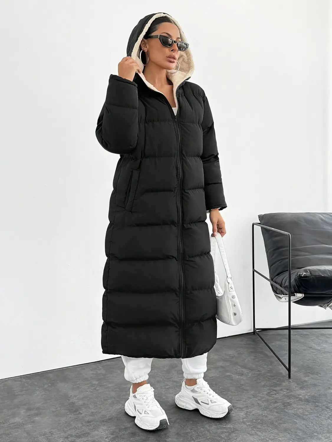 Black hooded quilted long puffer coat in black with a quilted design and white-lined hood for cold weather.