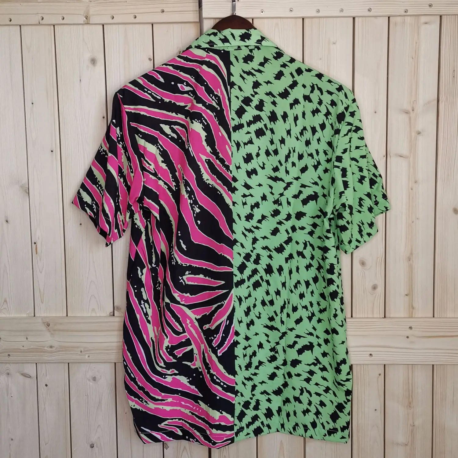A vibrant short-sleeved shirt featuring a bold split design with pink and black zebra stripes on one side and green with black leopard spots on the other.