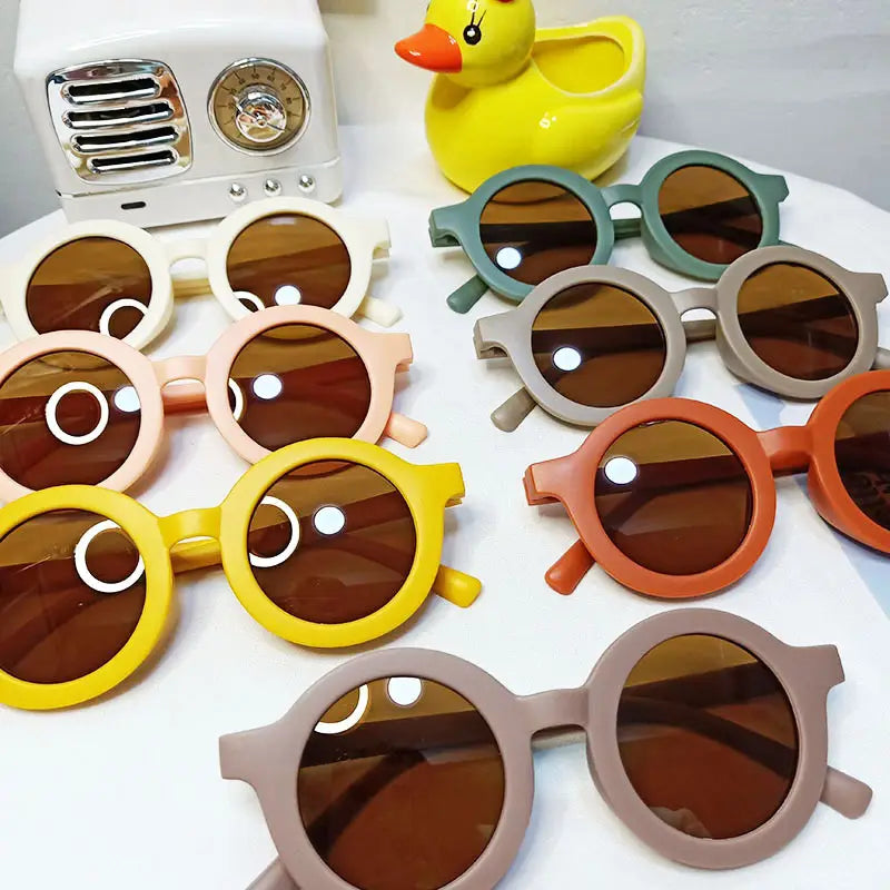 Un ensemble de lunettes de soleil pour chiens rétro rondes avec des montures orange, des verres marron et des motifs circulaires blancs ludiques sur les montures.