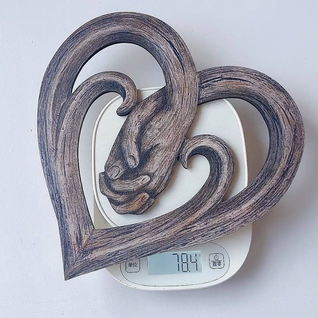 Herzförmige Wanddekoration aus dunklem Holz: ein rustikales, handgefertigtes Schnitzdesign ineinander verschlungener Hände, gefertigt aus Holz.