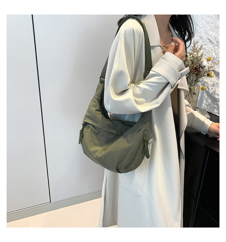 Olive green nylon crossbody bag with large capacity, zipper pockets, and tassel details designed as a hobo shoulder bag.