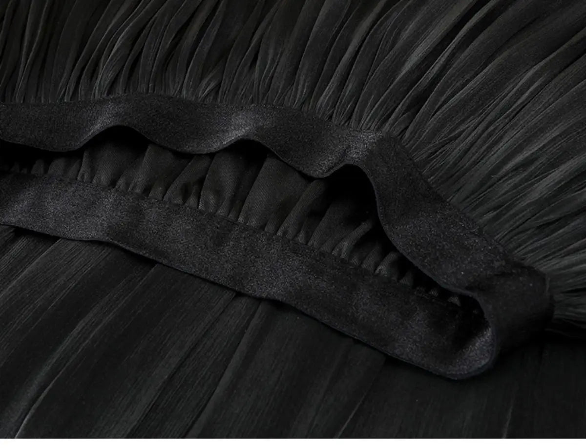 Ein schwarzer irrisierender Chiffon-Faltenrock mit weich fließendem Gewebe und glattem Satinabschluss am Saum.