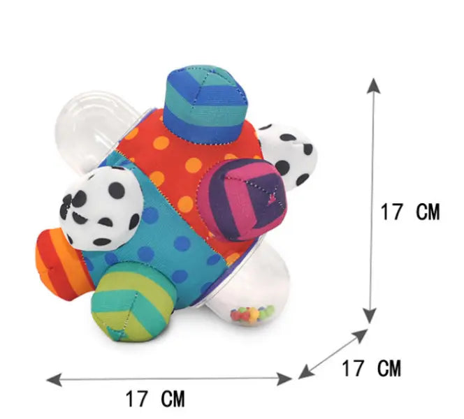 Plush baby rattle ball grasping toy with a colorful patchwork design featuring polka dots and stripes in vibrant orange teal pink and green for sensory play.