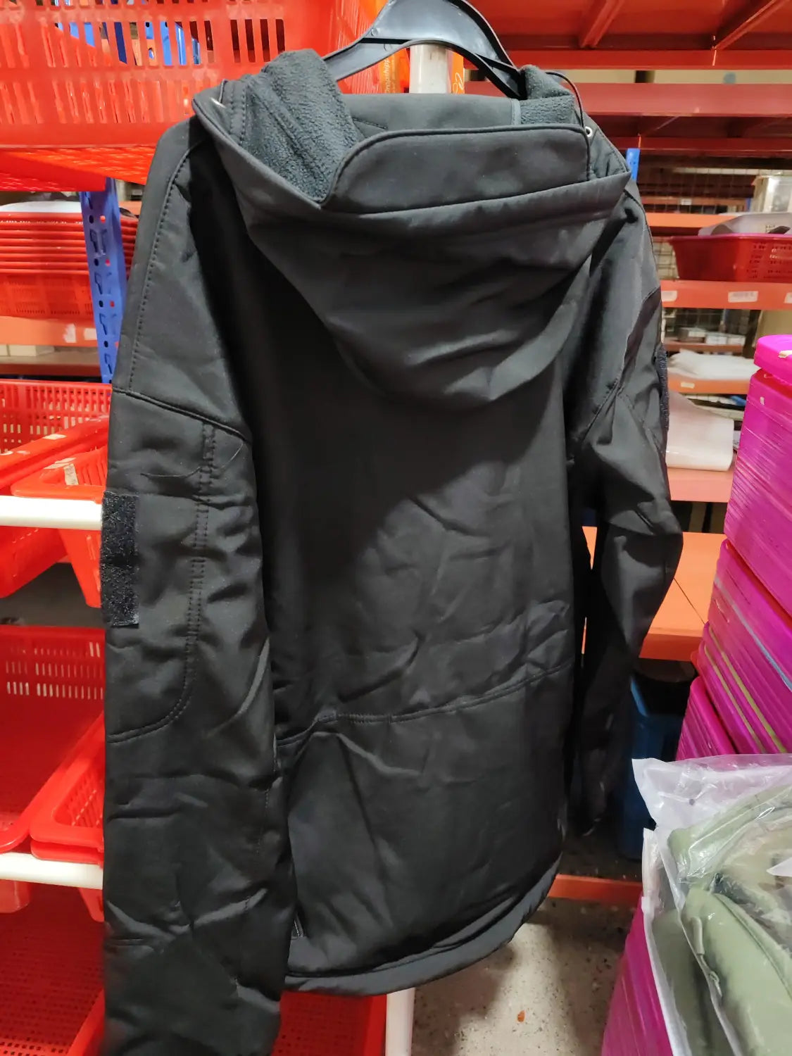 black hooded men’s waterproof tactical fleece soft shell jacket with quilted back and reinforced patch pockets shown from the back side