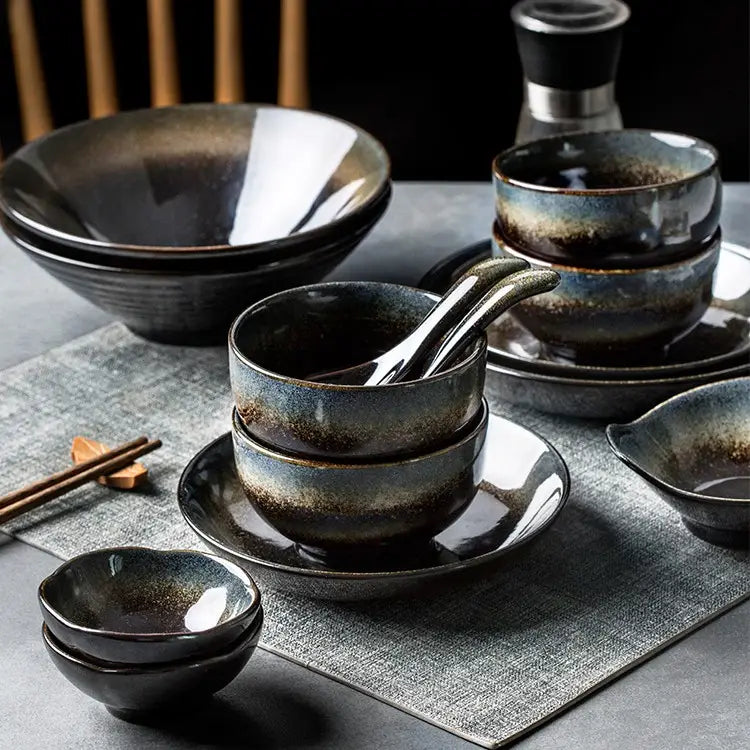 Set of dark ceramic bowls with a glossy gradient glaze transitioning from deep black to muted blue and brown in a ceramic tableware set with black and gold kiln glaze porcelain.