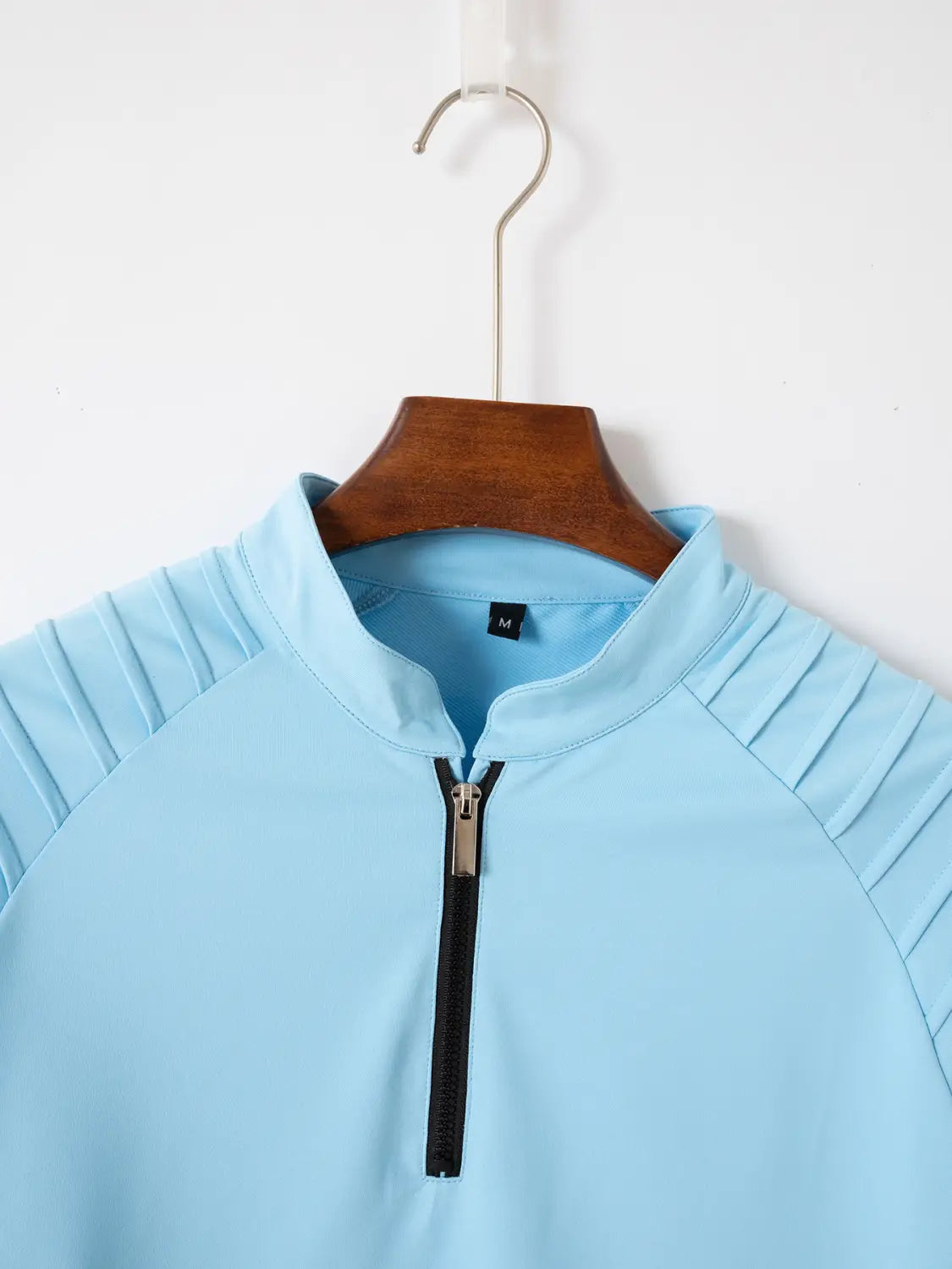 Herren-Quarter-Zip-Athletik-Poloshirt in Hellblau mit plissierten Schulterbereichen und schwarzem Reißverschluss, entworfen für Sport- und Freizeitkleidung