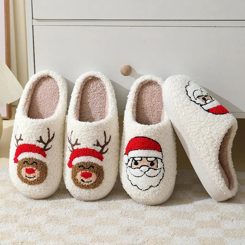 White plush festive embroidered santa and reindeer winter slippers with red hats, brown fur accents, and soft fleece lining.