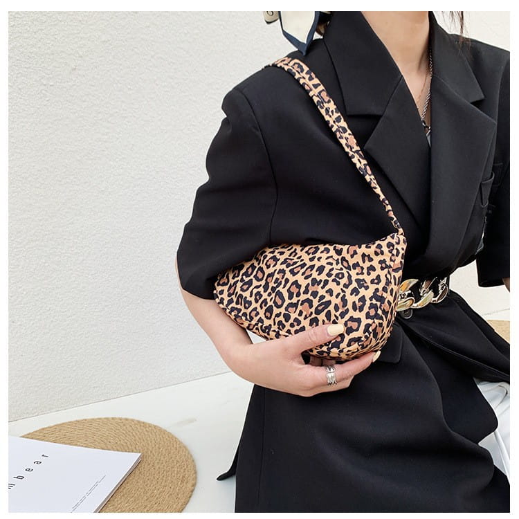 Sac bandoulière à imprimé léopard avec corps en tissu souple et sangle assortie, conçu comme un sac sous-bras.