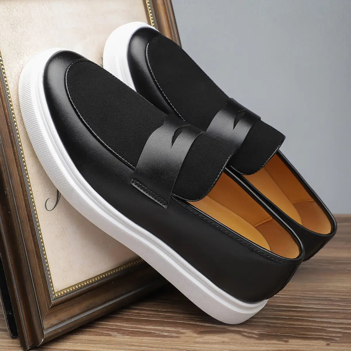 Herren-Leder-Slipper zum Hineinschlüpfen in Schwarz mit weißer Gummisohle und kontrastierender Innenfutterauskleidung in Hellbraun.