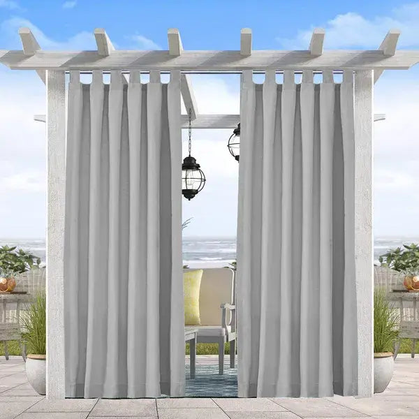 Hellgraue, wollene Verdunkelungsvorhänge für den Außenbereich mit vertikalen Falten hängen von einer weißen Pergola, die mit Gurten für den schweren Einsatz gesichert ist.