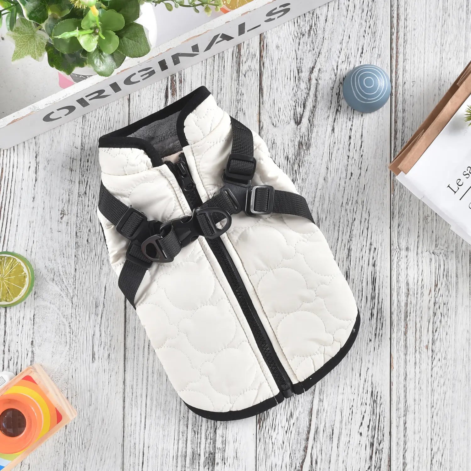 White quilted dog vest with black straps and zipper designed as a windproof warm pet coat.