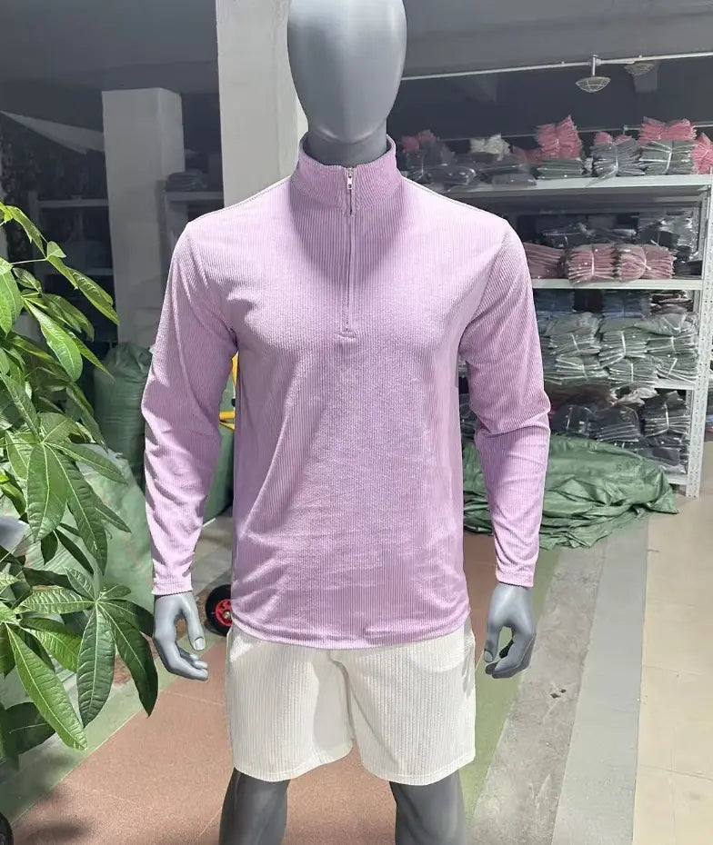 A light pink men’s ribbed knit half zip corduroy polo sweatshirt with a quarter-zip and matching white shorts.