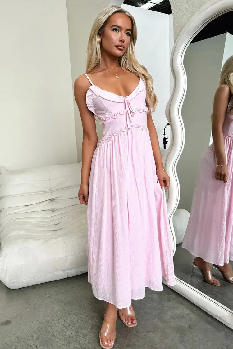 A soft pink flowing maxi vacation dress featuring delicate ruffled straps and a gathered waist.